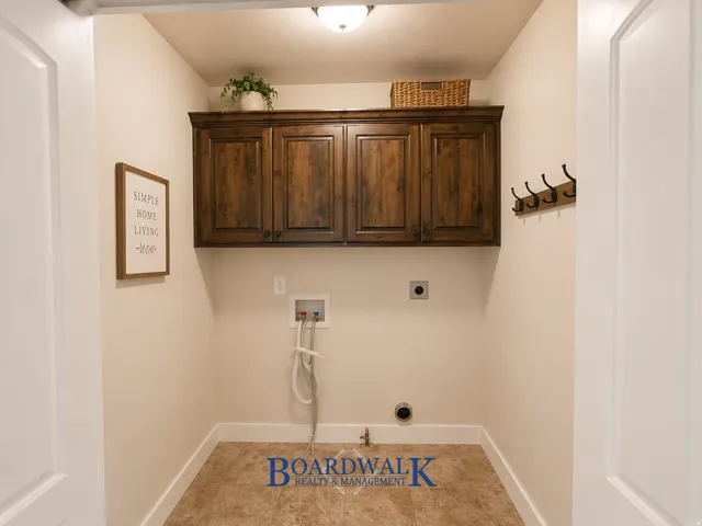Dedicated utility space featuring overhead wood cabinetry and tile flooring