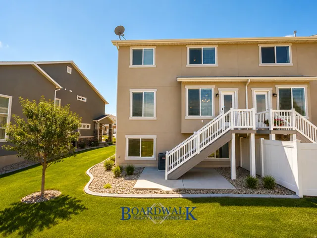 Exterior featuring a two-story design with light stucco siding, multiple windows, and two outdoor staircases with white railings