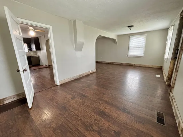 Spacious room featuring wood-finish flooring, light-toned wall paint, and a white paneled door