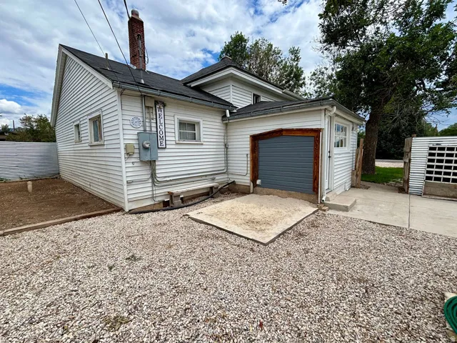 White siding exterior featuring a brick chimney and a dark gray roll-up garage door with wood trim