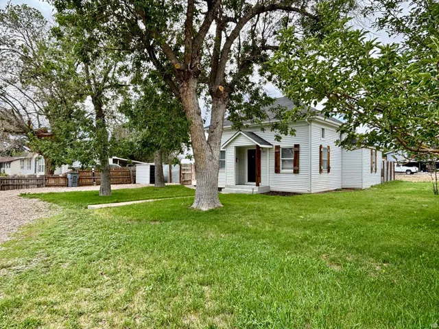 White-sided residence featuring a covered front porch, dark wood shutters, and a dark wood front door