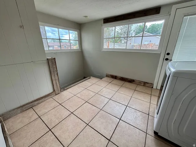 Tiled flooring with two large windows and a white door with dark hardware