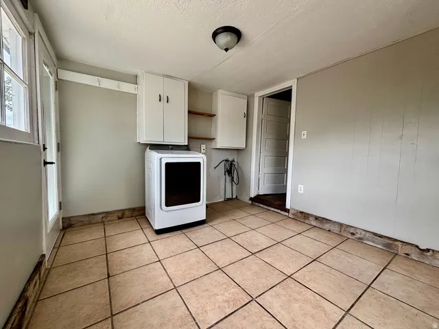 Mudroom featuring tile flooring, a glass-paneled exterior door, built-in wall hooks, and white cabinetry
