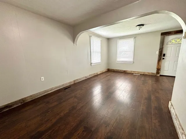 Open concept living area featuring dark wood-finish flooring, light-toned walls, and rustic wood baseboards