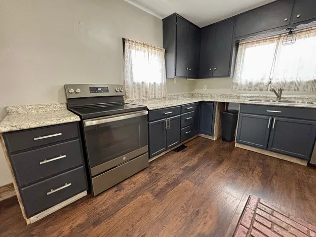 Kitchen featuring dark-finish cabinetry with silver-tone hardware, granite-look countertops, and stainless steel range