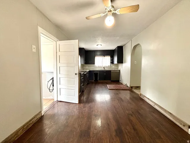 Wood-finish flooring extends throughout this expansive space, featuring a ceiling fan with light fixture