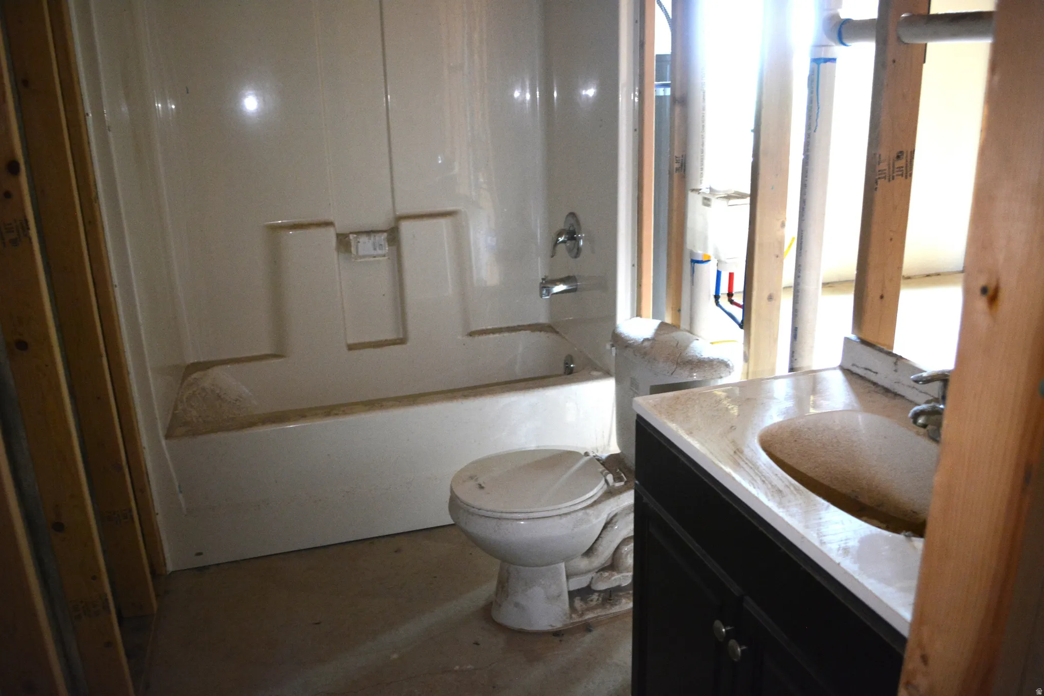 Bathroom featuring a white bathtub/shower combination, toilet, and a vanity with a countertop and undermount sink