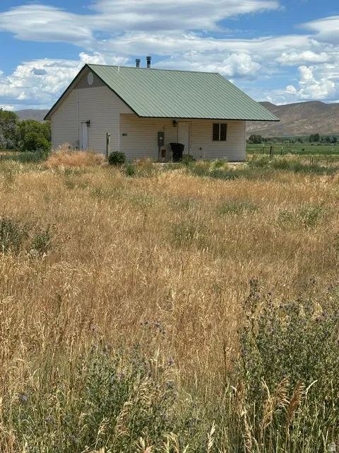 Gable-style building featuring a green metal roof and light-colored siding