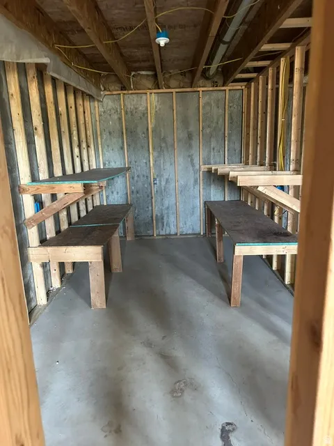 Unfinished basement area featuring exposed wood framing and concrete walls