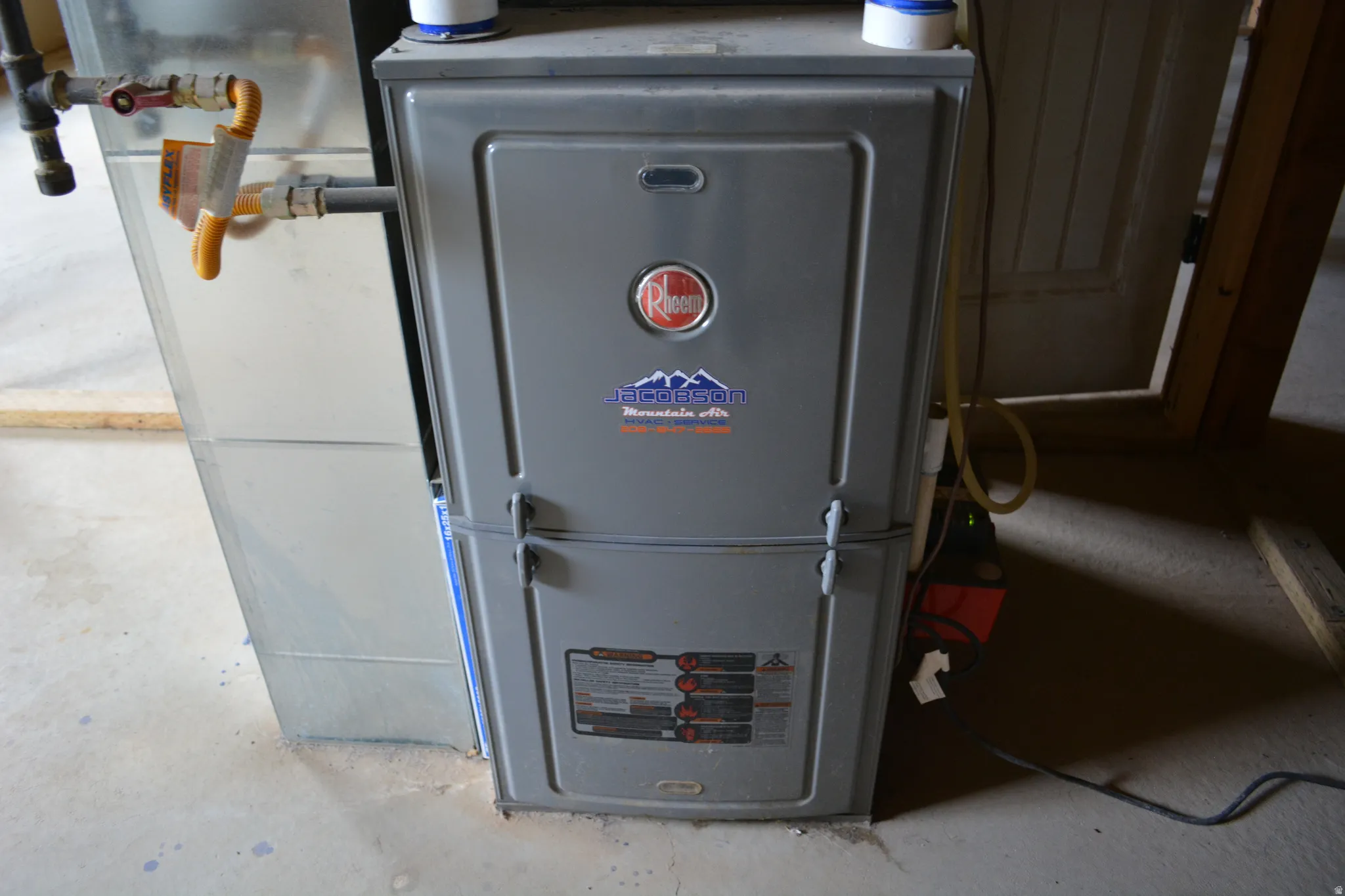 Rheem furnace unit with adjacent ductwork, gas line, and concrete flooring
