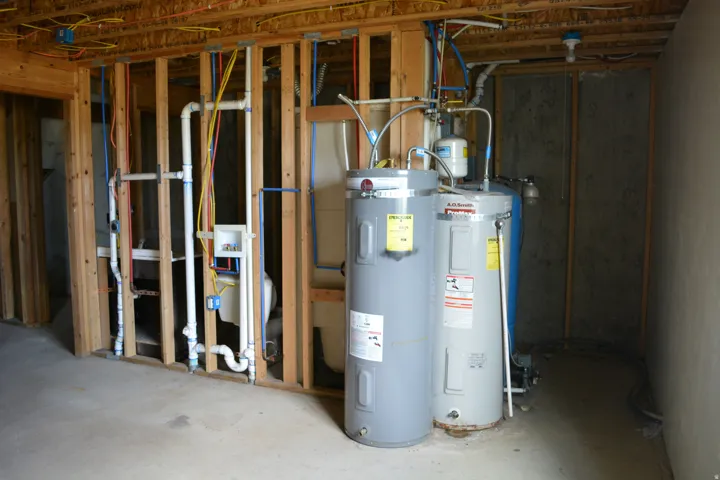 Unfinished interior space featuring exposed wood framing, concrete flooring, and visible plumbing and electrical infrastructure