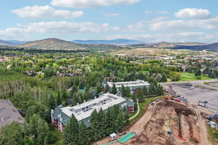Expansive aerial showcasing a complex of buildings with green sloped roofs amidst dense mature trees