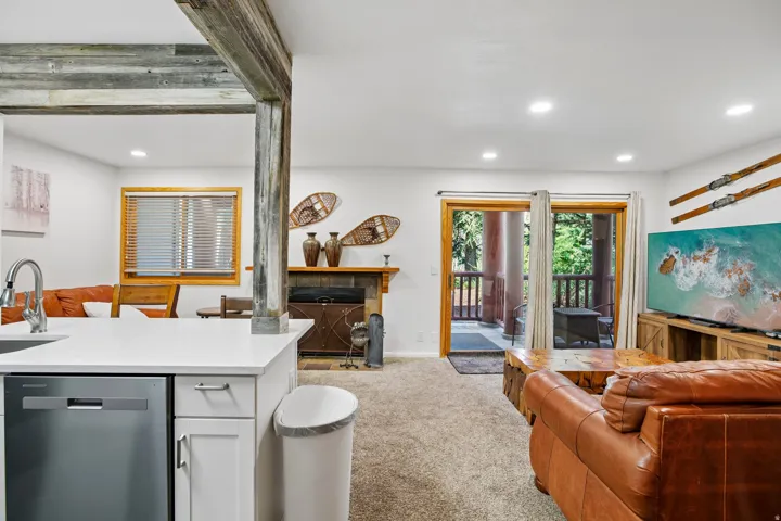 Open-concept living area featuring a kitchen island with white countertop, integrated stainless steel dishwasher, and recessed lighting