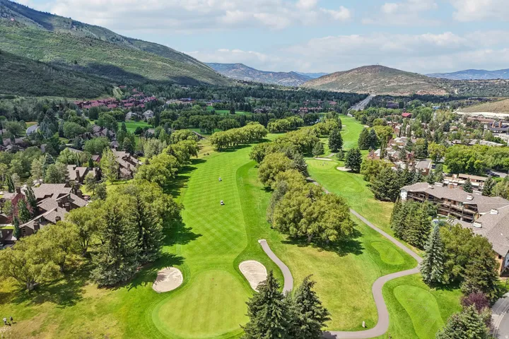 Expansive golf course fairway bordered by mature trees and residential properties