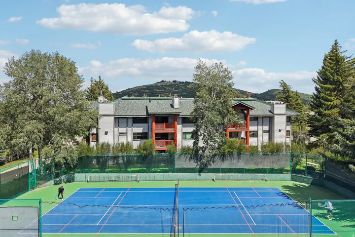 Full-size tennis court featuring a blue playing surface with white and red court lines