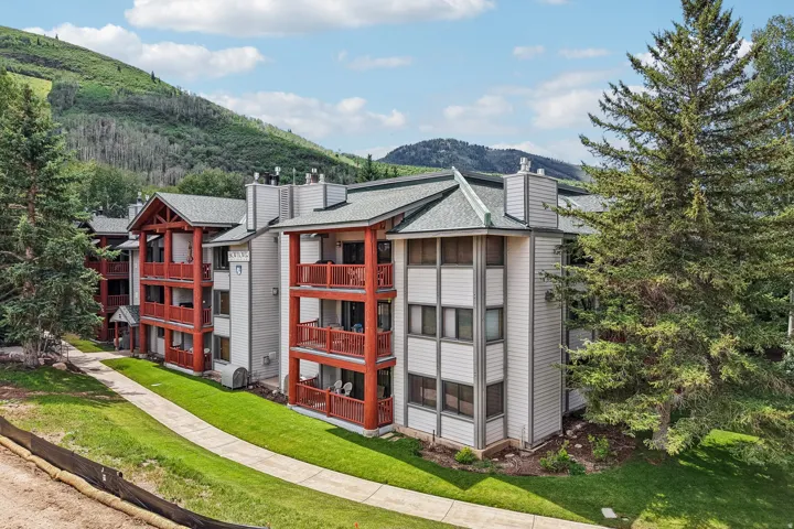 Multi-level condominium building featuring red wood-tone balconies and light-colored siding