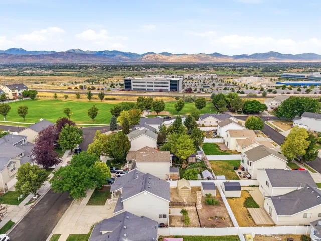 Residential development featuring varied home exteriors, mountain backdrop, green spaces, and a commercial building