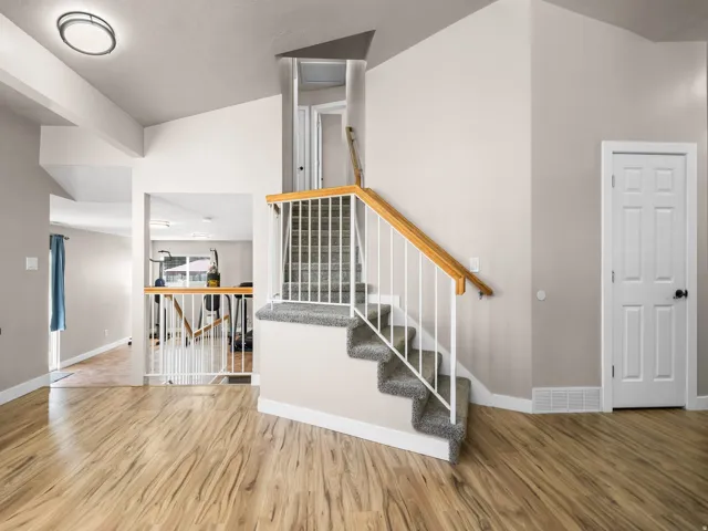 Interior staircase featuring carpeted treads, white balusters, and a natural wood handrail