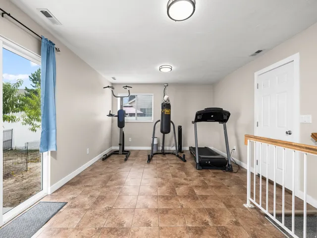 Spacious room with large format tile flooring, a sliding glass door, and abundant natural light