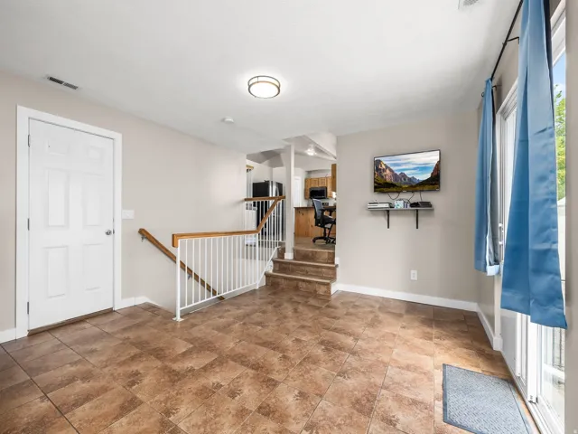 Entry-level living space featuring tile flooring, a white paneled door, and a staircase with a wood handrail and white balusters