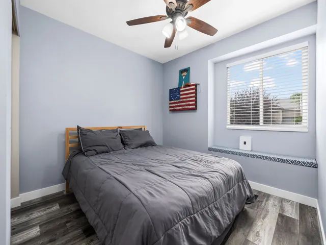 Room featuring a ceiling fan with integrated lighting, wood-finish flooring, and a large window with horizontal blinds