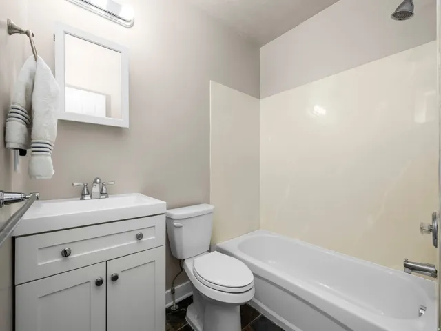 Bright bathroom featuring a white vanity with integrated sink, chrome faucet, and rectangular mirror