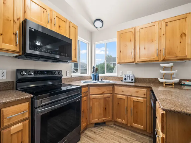 Kitchen featuring light wood cabinetry, stone-finish countertops, and wood-finish flooring