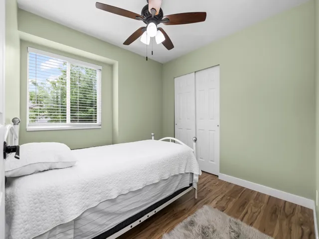 Room featuring wood-finish flooring, a window with horizontal blinds, and a built-in ceiling fan with integrated lighting