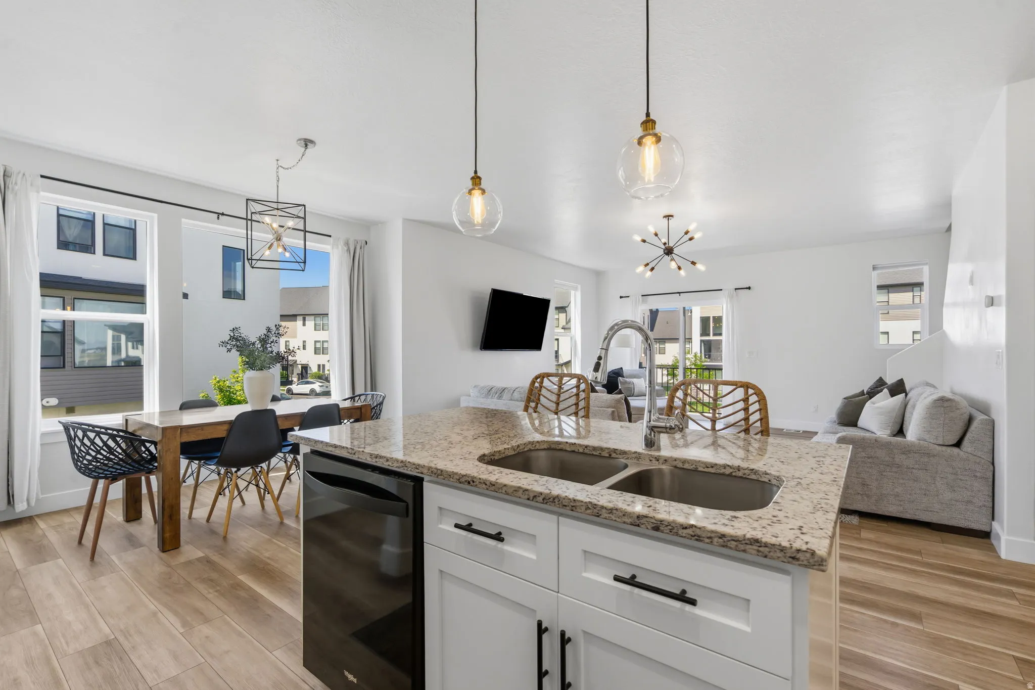 Kitchen island featuring a double basin stainless steel sink with a high-arc faucet, granite countertop, and integrated dishwasher