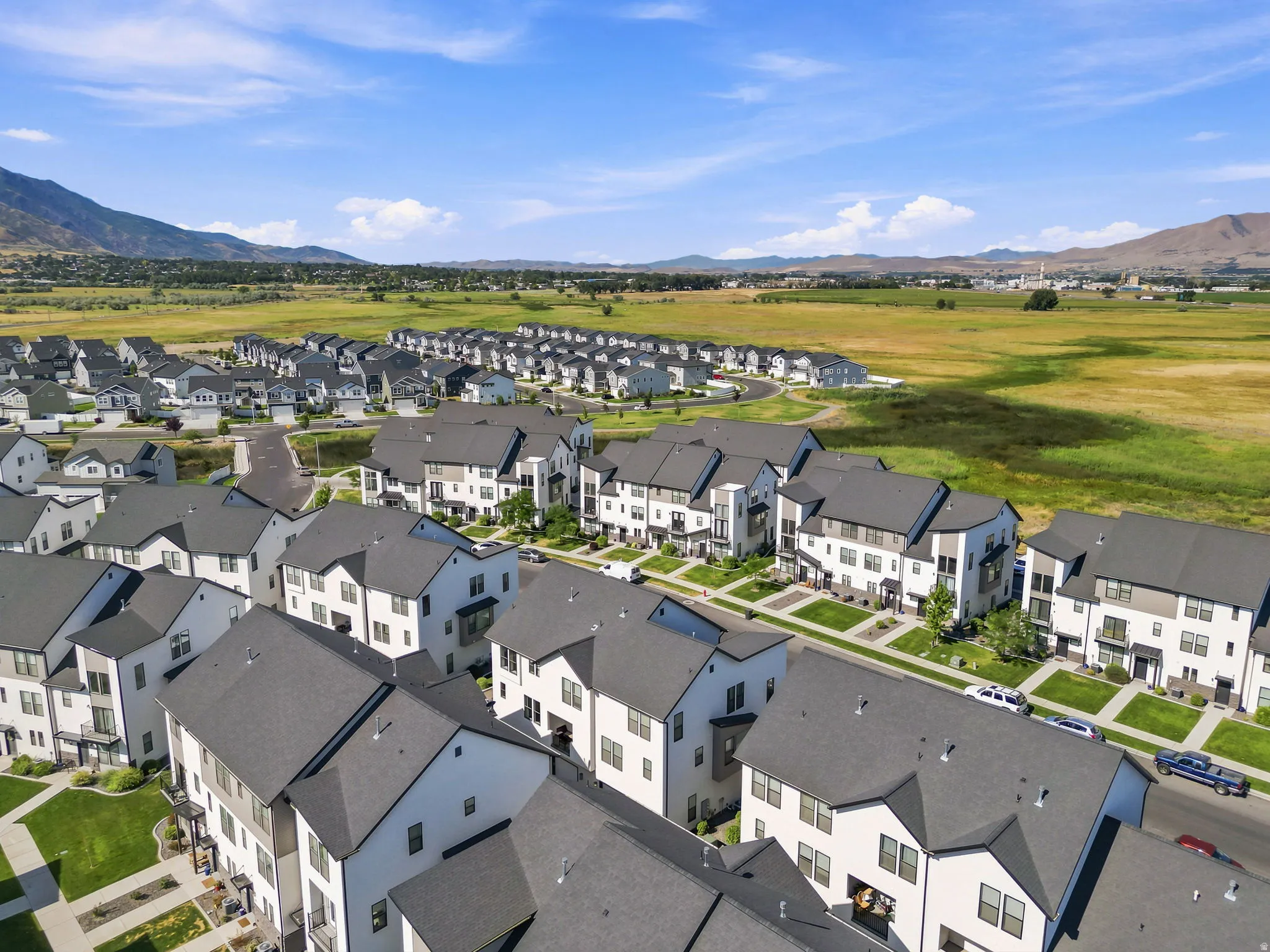 Modern residential community featuring multi-story townhomes with dark roofing and white and grey facades
