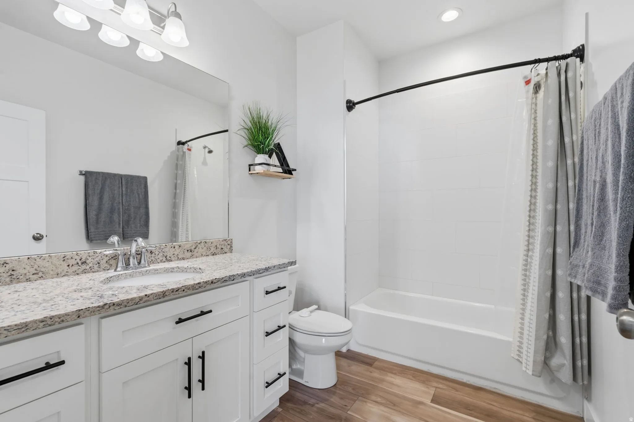 Bathroom featuring a single vanity with stone-finish countertop, undermount sink, and white cabinetry