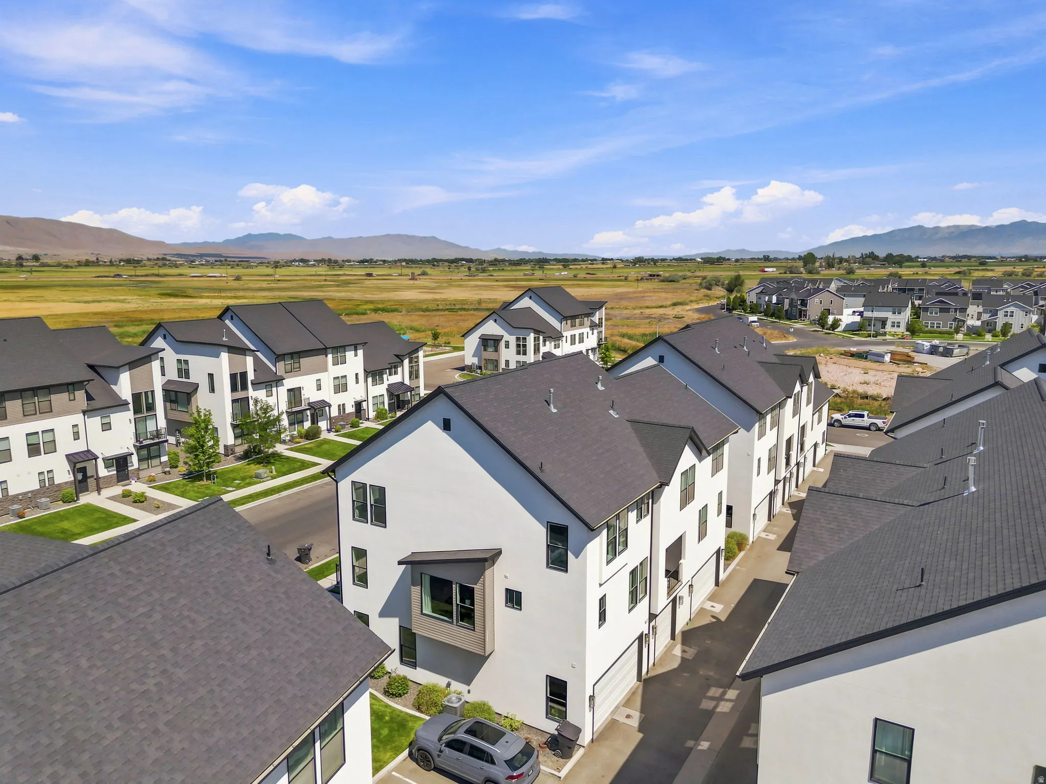 Modern townhome development featuring a consistent architectural design with dark shingle roofs, crisp white and neutral-toned facades, and multiple windows