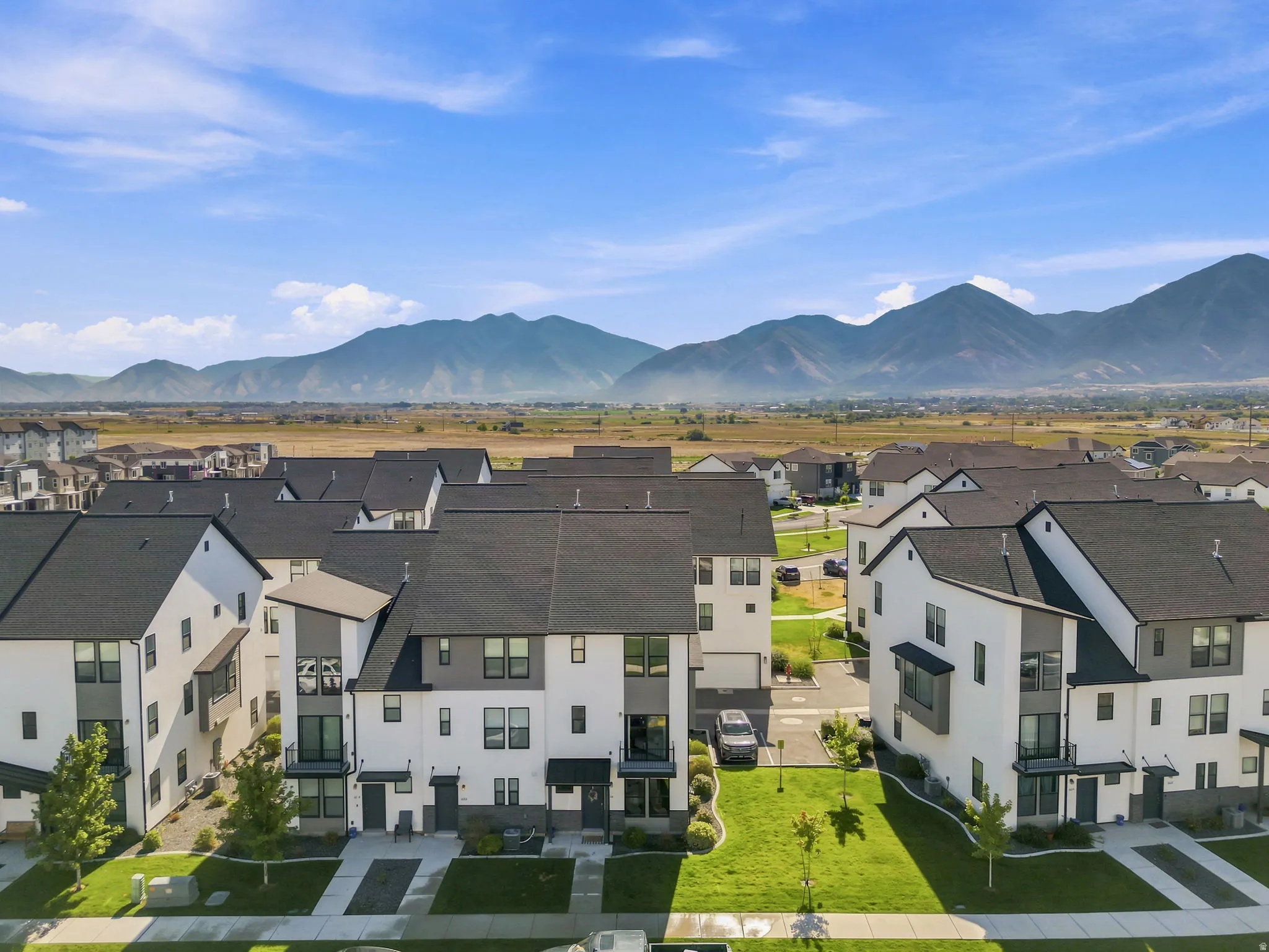 Contemporary townhome community featuring a uniform aesthetic of white and gray exteriors with dark roofing