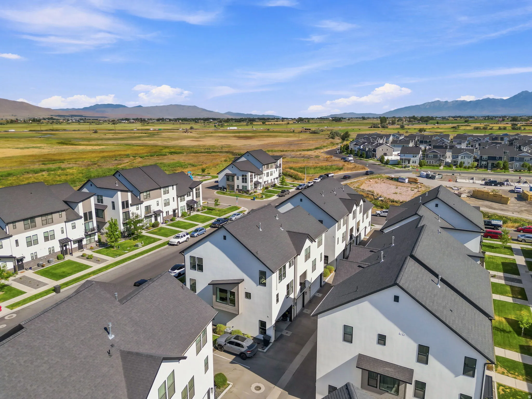 Aerial perspective showcasing a community of multi-story residences with dark roofs and light-colored exteriors