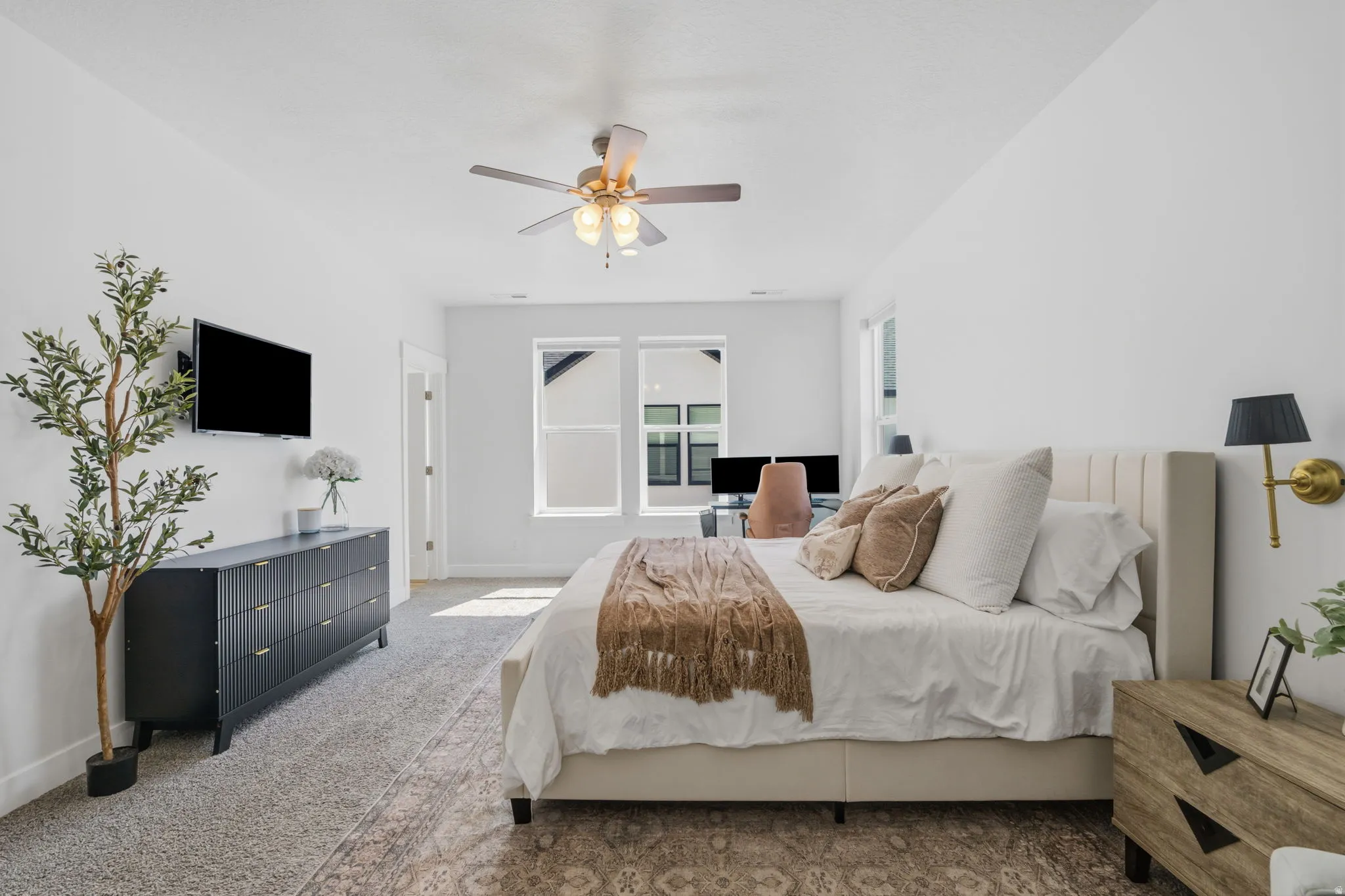 Bright room with dual windows, neutral wall tones, textured carpet, and a ceiling fan with integrated lighting