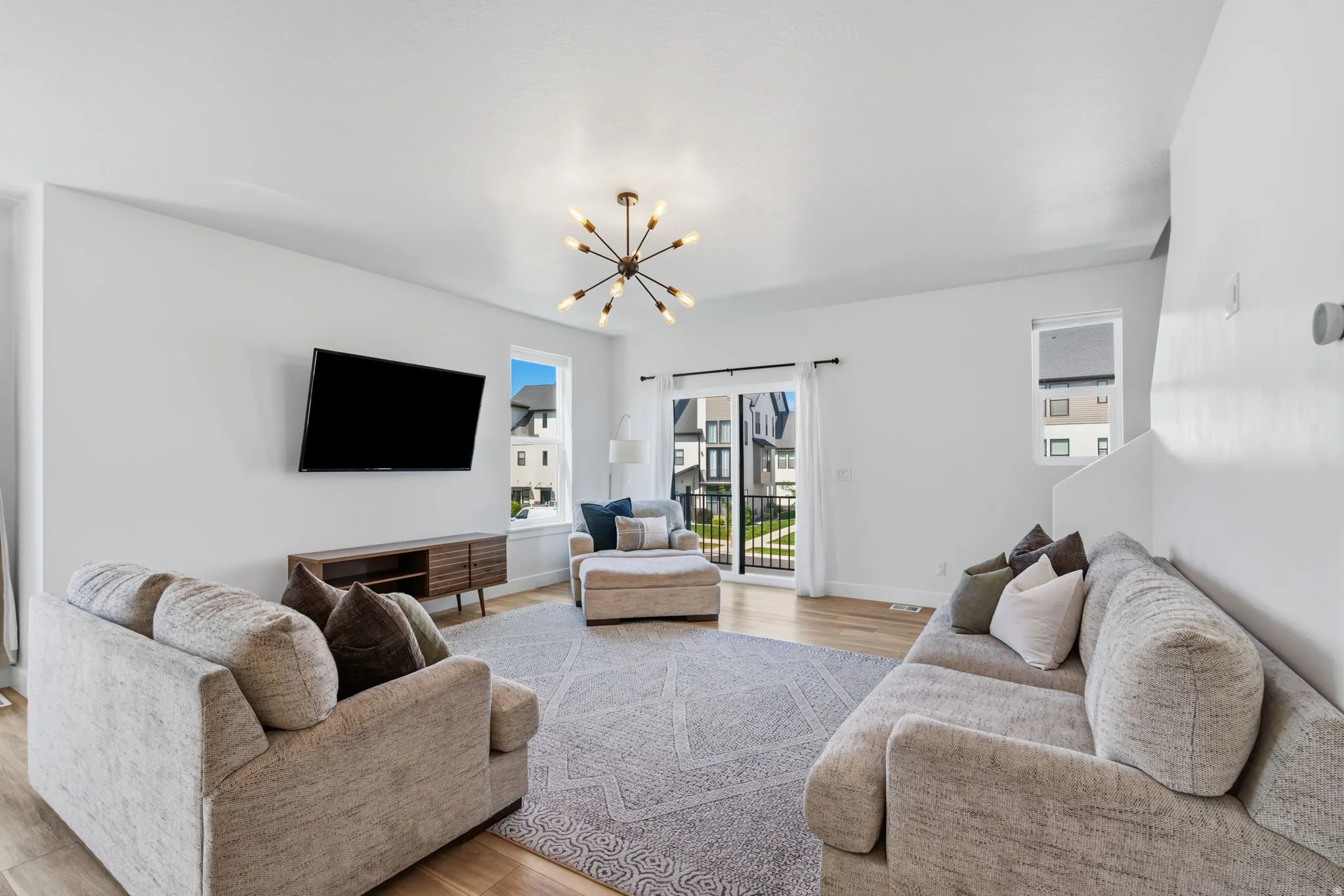 Spacious living area featuring light wood-finish flooring and bright white walls