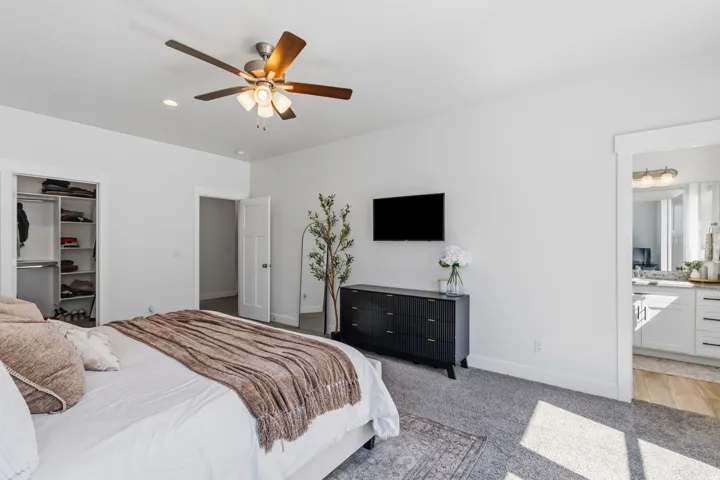 Spacious bedroom featuring light gray carpeting, a ceiling fan with integrated lighting, and recessed lighting