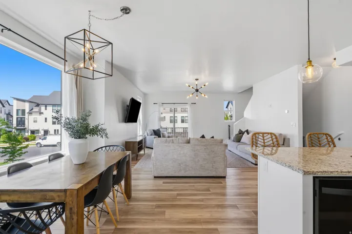 Open-concept living space featuring wood-finish flooring, a large picture window, and a contemporary chandelier
