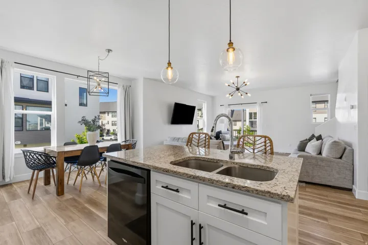 Kitchen island featuring a double basin stainless steel sink with a high-arc faucet, granite countertop, and integrated dishwasher