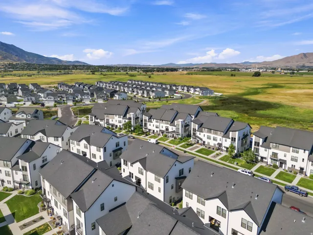 Modern residential community featuring multi-story townhomes with dark roofing and white and grey facades