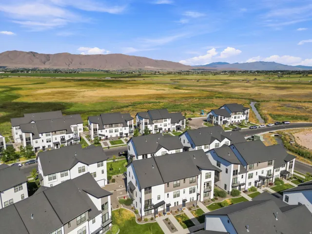 Aerial perspective showcasing a community of modern townhomes with contrasting dark roofs and light-colored exteriors