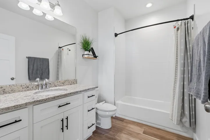 Bathroom featuring a single vanity with stone-finish countertop, undermount sink, and white cabinetry