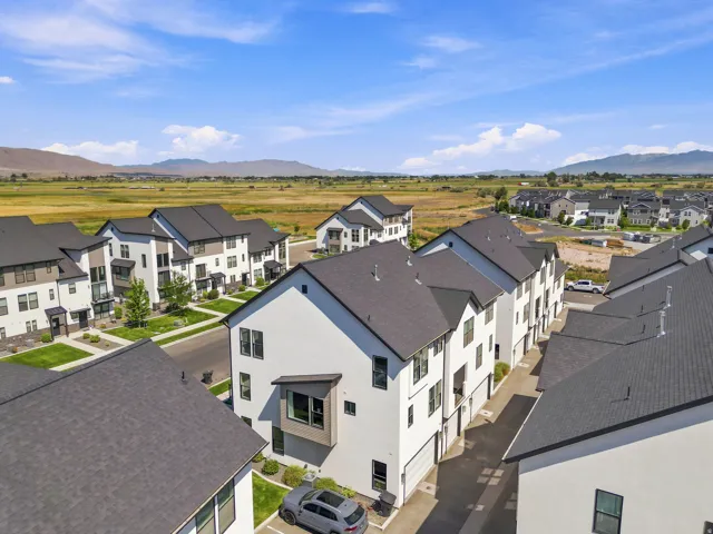 Modern townhome development featuring a consistent architectural design with dark shingle roofs, crisp white and neutral-toned facades, and multiple windows