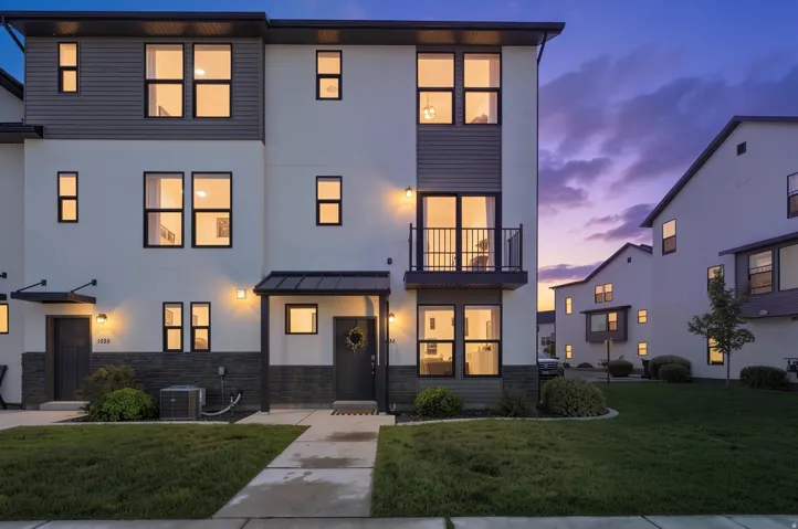 Modern multi-story exterior with a balcony, dark trim windows, and a combination of horizontal siding and stucco finishes
