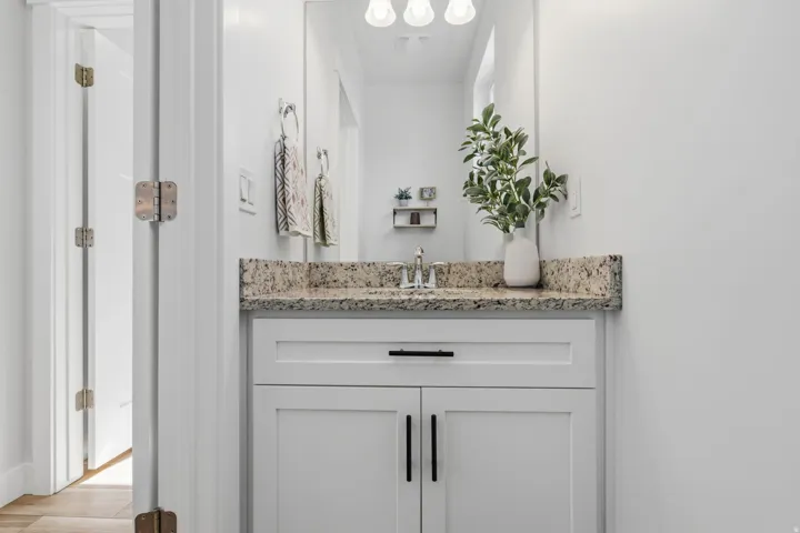 Bathroom vanity featuring a speckled countertop, undermount sink, and shaker-style cabinetry with matte black hardware