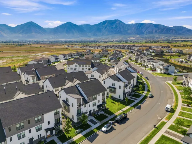 Modern residential neighborhood with mountain scenery, featuring contemporary architecture, paved streets, and manicured landscaping