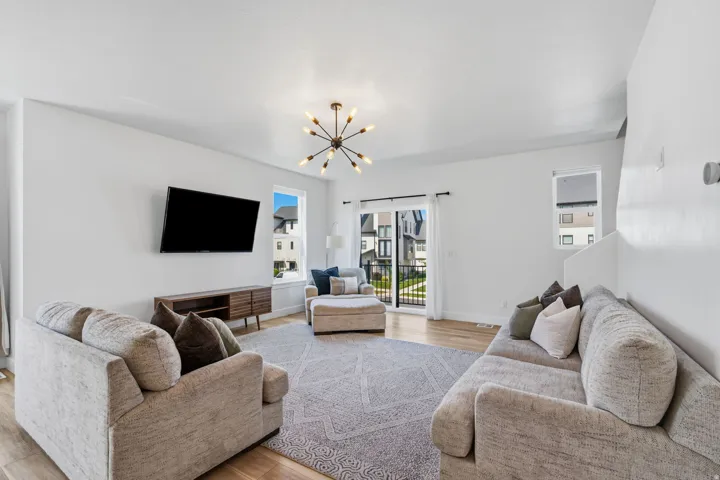 Spacious living area featuring light wood-finish flooring and bright white walls