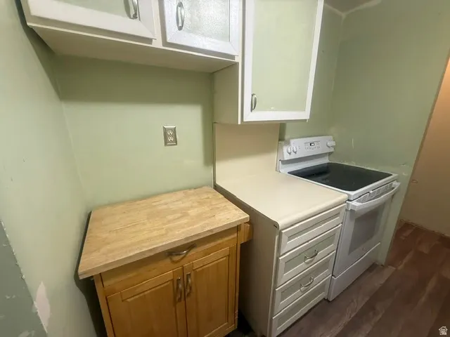 Kitchen area featuring a white electric range, light-colored countertops, and upper cabinetry