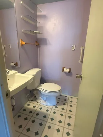 Bathroom featuring patterned floor tiles, a wall-mounted sink, and a toilet and full bath