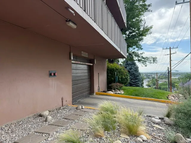 Ground-level access with a roll-up door, exterior lighting, and a stepped pathway featuring decorative gravel and natural stone elements